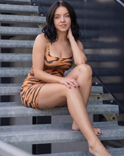 Sydney Sweeney in leopard print dress on outdoor steps
